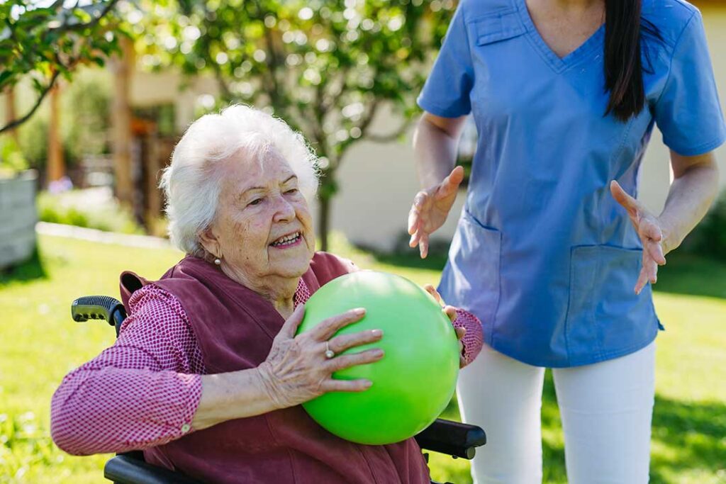 Two older adults smiling while decorating a cozy common room with personal photos and keepsakes.
