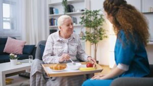 Older adults seated around a table painting, arranging flowers, and sharing creative materials.